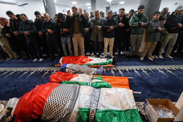 Palestinian men pray over the bodies of four members of the same family, two children and their parents, killed by Israeli soldiers in their vehicle, during their funeral in the Israeli-occupied West Bank's northern town of Tammun on March 15, 2026. Israeli forces shot dead four members of a Palestinian family, a 37-year-old man, his 35-year-old wife and two boys aged five and seven, in the occupied West Bank, the Palestinian health ministry reported, while Israel said troops opened fire over a perceived safety threat. According to an AFP tally based on Palestinian health ministry figures, Israeli troops or settlers have killed at least 1,045 Palestinians -- many of them militants, but also scores of civilians -- in the West Bank since the start of the Gaza war. (Photo by JAAFAR ASHTIYEH / AFP)