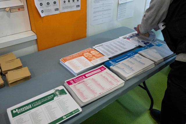 A local residents collects the ballot papers upon arrival at a polling station to cast their ballot during the first round of France's 2026 municipal elections in Marseille, southern France, on March 15, 2026. (Photo by Elodie CLEMENT / AFP)