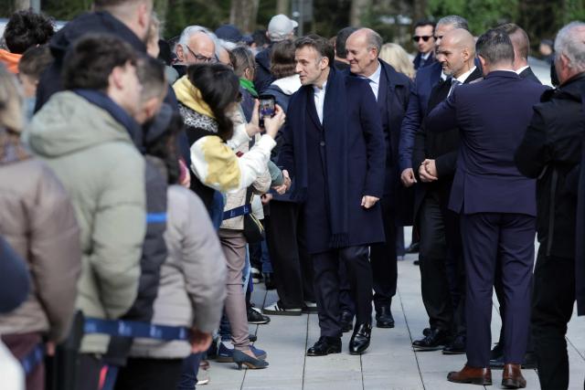 France's President Emmanuel Macron (C) shakes hands with inhabitatns as he arrives to vote during the first round of France's 2026 municipal elections in Le Touquet, northern France, on March 15, 2026. (Photo by Ludovic MARIN / AFP)