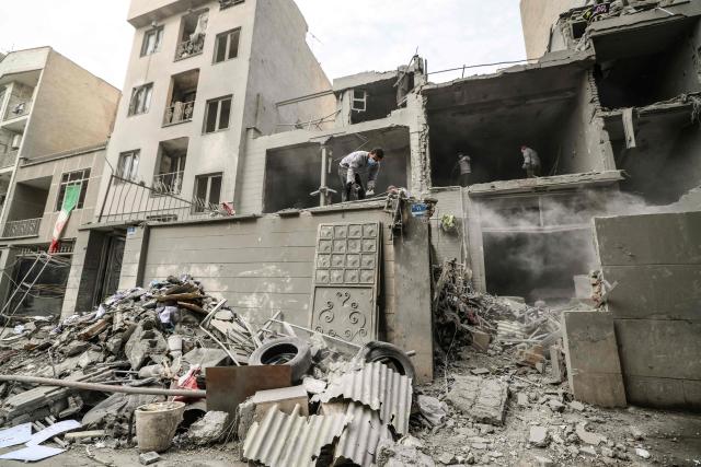 Iranian clear the debris from damaged homes in the Iranian capital Tehran on March 15, 2026. Iran's Foreign Minister said in an interview published on March 15, that the war pitting his country against the United States and Israel will only end when Tehran can be certain it will not be restarted (Photo by Atta KENARE / AFP) / 
