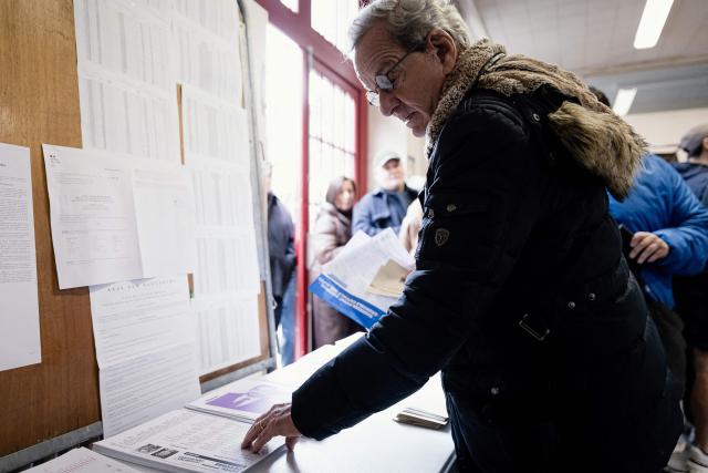 Former Mayor of Grenoble and right-wing Les Republicains (LR) party candidate for his re-election Alain Carignon collects the ballot papers during the first round of France's 2026 municipal elections in Grenoble, central France on March 15, 2026. (Photo by Maxime GRUSS / AFP)