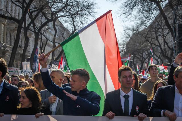Hungarian opposition leader and president of the TISZA (Respect and Freedom) party Peter Magyar (C-L) raises a national flag of Hungary as he marches alongside protesters during a "National March” in Budapest, Hungary on March 15, 2026, on the 178th anniversary of the Hungarian Revolution and War of Independence of 1848-1849. The 1848-1849 revolution in the Kingdom of Hungary grew into a war for independence from the Austrian Empire, ruled by the Habsburg dynasty. (Photo by Ferenc ISZA / AFP)