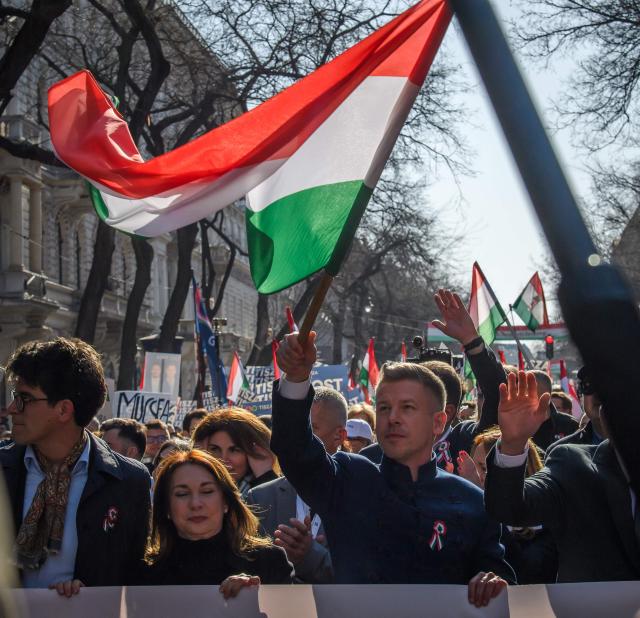 Hungarian opposition leader and president of the TISZA (Respect and Freedom) party Peter Magyar (R) raises a national flag of Hungary as he marches alongside protesters during a "National March” in Budapest, Hungary on March 15, 2026, on the 178th anniversary of the Hungarian Revolution and War of Independence of 1848-1849. The 1848-1849 revolution in the Kingdom of Hungary grew into a war for independence from the Austrian Empire, ruled by the Habsburg dynasty. (Photo by Ferenc ISZA / AFP)