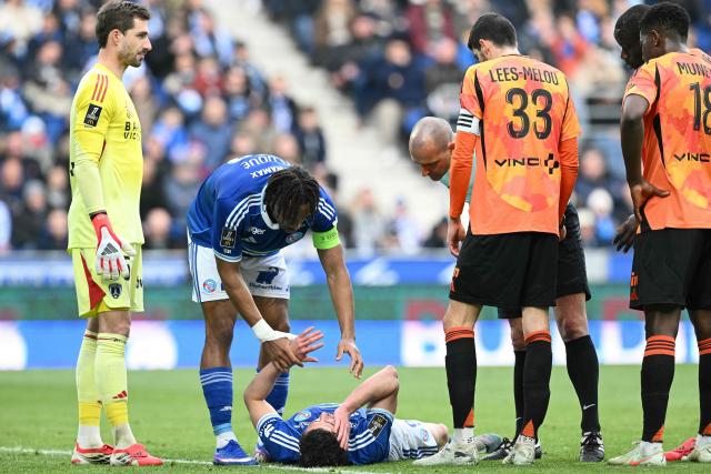 Strasbourg’s Ivorian defender #22 Guela Doue (2nd L) helps Strasbourg’s Argentine forward #09 Joaquin Panichelli during the French L1 football match between RC Strasbourg Alsace and Paris FC at the Stade de la Meinau in Strasbourg, eastern France on March 15, 2026. (Photo by SEBASTIEN BOZON / AFP)