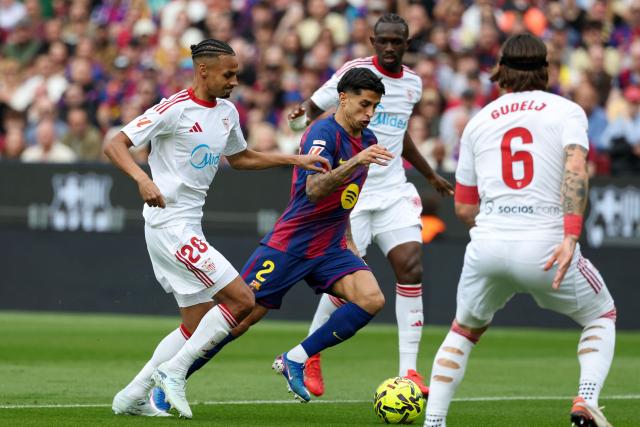 Barcelona's Portuguese defender #02 Joao Cancelo (C) runs with the ball challenged by Sevilla's Swiss midfielder #20 Djibril Sow during the Spanish League football match between FC Barcelona and Sevilla FC at the Camp Nou Stadium in Barcelona, on March 15, 2026. (Photo by Lluis GENE / AFP)