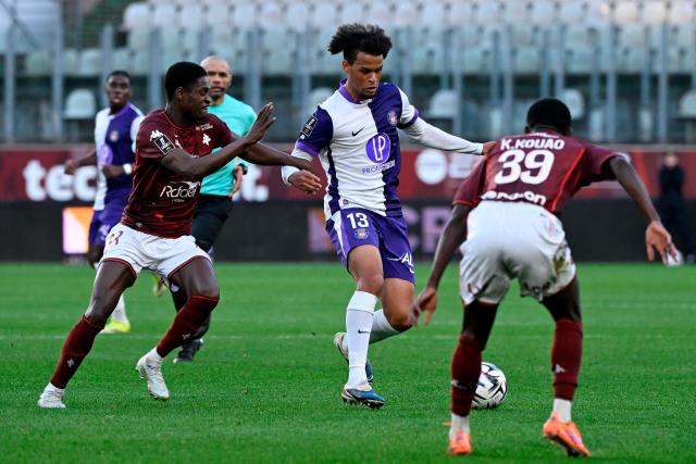 Toulouse's Canadian forward #13 Jacen Russel-Rowe (C) fights for the ball with Metz's Senegalese defender #38 Sadibou Sane (L) and Metz's Ivorian defender #39 Koffi Kouao (R) during the French L1 football match between FC Metz and Toulouse FC at the Stade Saint-Symphorien in Longeville-les-Metz, eastern France, on March 15, 2026. (Photo by Jean-Christophe VERHAEGEN / AFP)