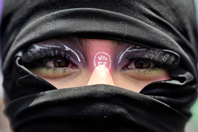 A masked woman takes part in a march to commemorate the International Women's Day in Bogota on March 15, 2026. (Photo by Diana SANCHEZ / AFP)