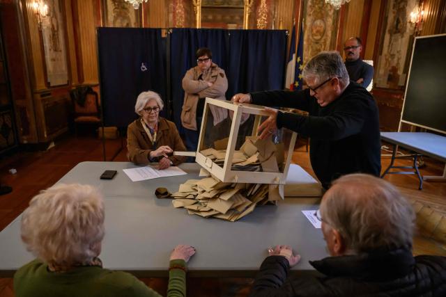Officials empty a ballot box following the closing of voting during municipal elections at the city hall in Perpignan, south-western France, on March 15, 2026. (Photo by Ed JONES / AFP)
