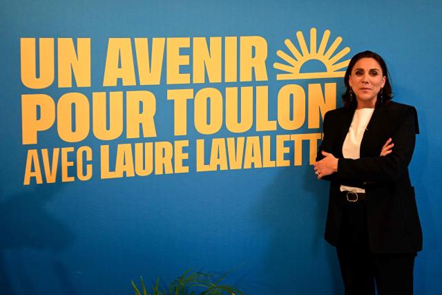 Toulons far-right Rassemblement National (RN) party mayoral candidate, Laure Lavalette poses in front of a campaign poster at her campaign headquarters after the first results of the first round of France's 2026 municipal elections in Toulon, southern France, on March 15, 2026. Lavalette has emerged as the frontrunner in the first round of the municipal elections in Toulon, with between 39.4% and 42% of the vote according to estimates, ahead of the outgoing mayor in a city where the left will not be contesting the second round. (Photo by Miguel MEDINA / AFP)
