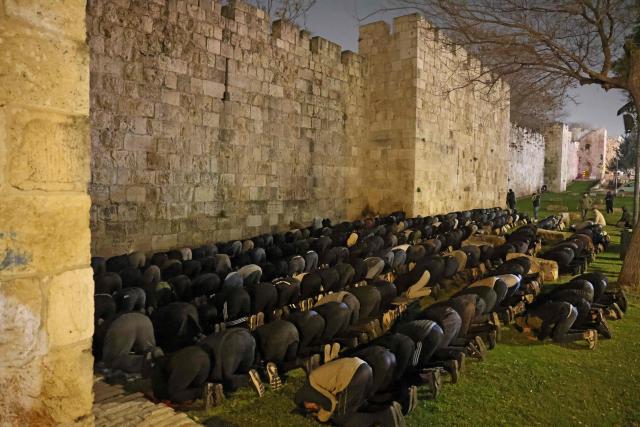 Palestinian Muslims pray outside the Old City of Jerusalem on Laylat al-Qadr or Night of Destiny, one of the holiest nights during the holy fasting month of Ramadan on March 15, 2026, as the nearby al-Aqsa Mosque remains closed following the outbreak of the US-Israel war with Iran on February 28. Israel has shut all holy sites in east Jerusalem's Old City for security reasons after it began airstrikes with the United States against Iran that have sparked a regional war. (Photo by AHMAD GHARABLI / AFP)