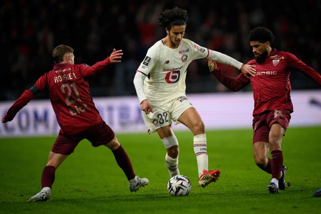 Lille's French midfielder #32 Ayyoub Bouaddi (C) fights for the ball with Rennes' French midfielder #21 Valentin Rongier (L) during the French L1 football match between Stade Rennais and Losc Lille at the Roazhon Park stadium in Rennes, western France on March 15, 2026. (Photo by Loic VENANCE / AFP)