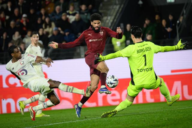 Rennes' French midfielder #45 Mahdi Camara (C) shoots towards goal as Lille's Turkish goalkeeper #01 Berke Ozer (R) tries to block during the French L1 football match between Stade Rennais and Losc Lille at the Roazhon Park stadium in Rennes, western France on March 15, 2026. (Photo by Loic VENANCE / AFP)