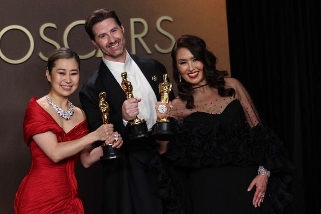 TOPSHOT - (L/R) South Korean-Canadian storyboard artist and writer, US film director Chris Appelhans, and film producer Michelle Wong pose in the press room with the Oscar for Best Animated Feature Film for "KPop Demon Hunters" during the 98th Annual Academy Awards at the Dolby Theatre in Hollywood, California on March 15, 2026. (Photo by VALERIE MACON / AFP)