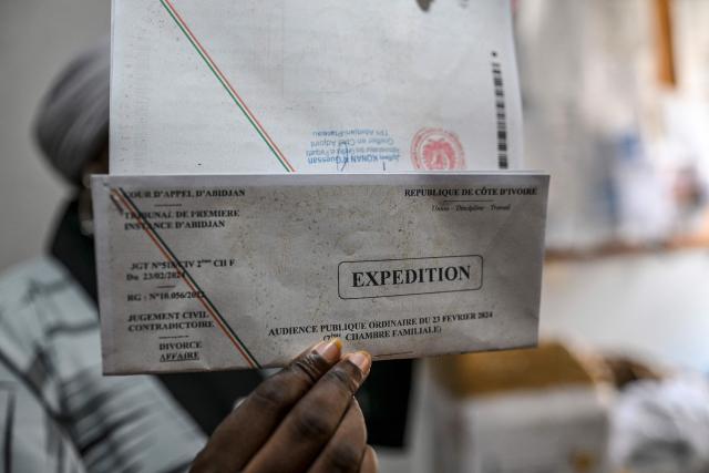 A woman holds her divorce certificate in Abidjan on March 10, 2026. In Ivory Coast the law permits divorce, it remains taboo, and numerous obstacles discourage women from leaving their husbands.
With only 1,835 divorce applications out of 30,912 marriages in 2024, according to official figures, four times fewer than in France, this procedure is a marginal reality in the country, as in many places on the continent. (Photo by Issouf SANOGO / AFP)