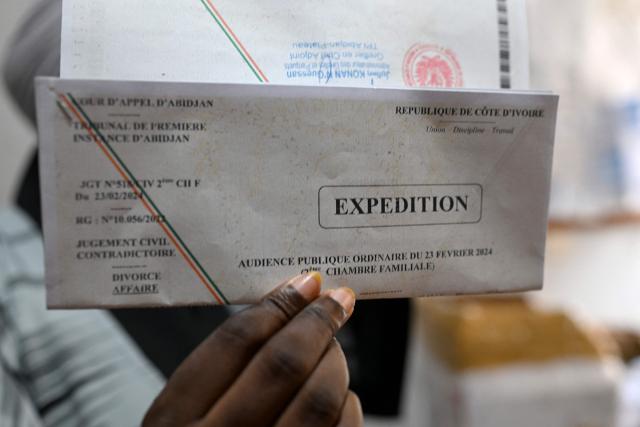 A woman holds her divorce certificate in Abidjan on March 10, 2026. In Ivory Coast the law permits divorce, it remains taboo, and numerous obstacles discourage women from leaving their husbands.
With only 1,835 divorce applications out of 30,912 marriages in 2024, according to official figures, four times fewer than in France, this procedure is a marginal reality in the country, as in many places on the continent. (Photo by Issouf SANOGO / AFP)