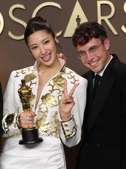 TOPSHOT - (L/R) Jeong Hoon Seo, South Korean-US singer Ejae and US songwriter Mark Sonnenblick pose in the press room with the Oscar for Best Music (Original Song) for "Golden" from "KPop Demon Hunters" during the 98th Annual Academy Awards at the Dolby Theatre in Hollywood, California on March 15, 2026. (Photo by VALERIE MACON / AFP)