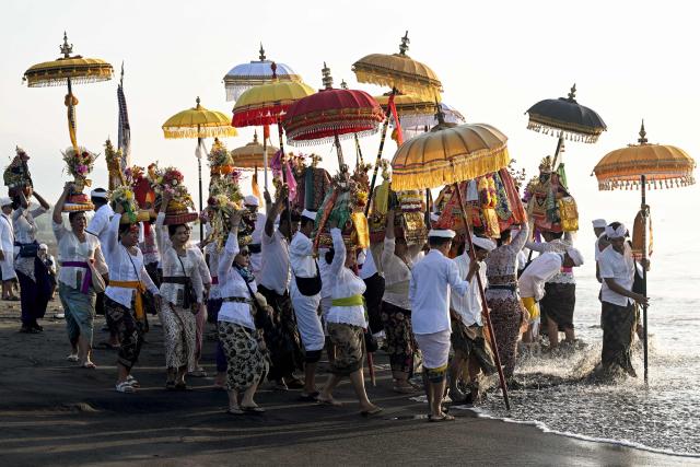 Hindu devotees take part in a Melasti ceremony prayer at a beach in Denpasar on Indonesia's resort island of Bali on March 16, 2026. Melasti is a purification festival which is held several days before "Nyepi", the day of silence, when Hindu devotees are not allowed to work, travel or take part in any indulgence (Photo by SONNY TUMBELAKA / AFP)