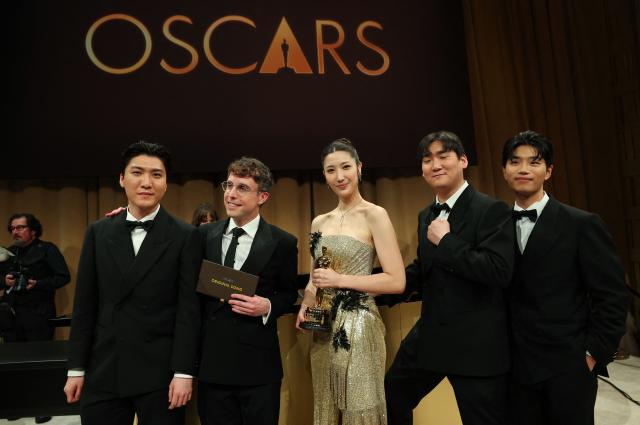 South Korean-US singer Ejae holds the Oscar for Best Music (Original Song) for "Golden" from "KPop Demon Hunters" with Jeong Hoon Seo (L), US songwriter Mark Sonnenblick (2L), Hee Dong Nam (2R) and Yu Han Lee (L) during the 98th Annual Academy Awards Governors Ball at the Dolby Theatre in Hollywood, California on March 15, 2026. (Photo by ANGELA WEISS / AFP)