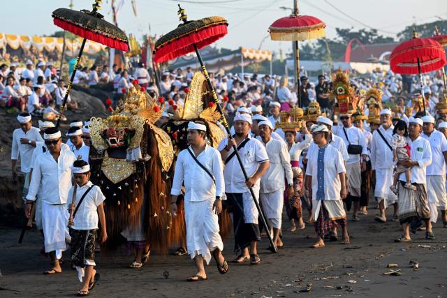 Hindu devotees take part in a Melasti ceremony prayer at a beach in Denpasar on Indonesia's resort island of Bali on March 16, 2026. Melasti is a purification festival which is held several days before "Nyepi", the day of silence, when Hindu devotees are not allowed to work, travel or take part in any indulgence (Photo by SONNY TUMBELAKA / AFP)