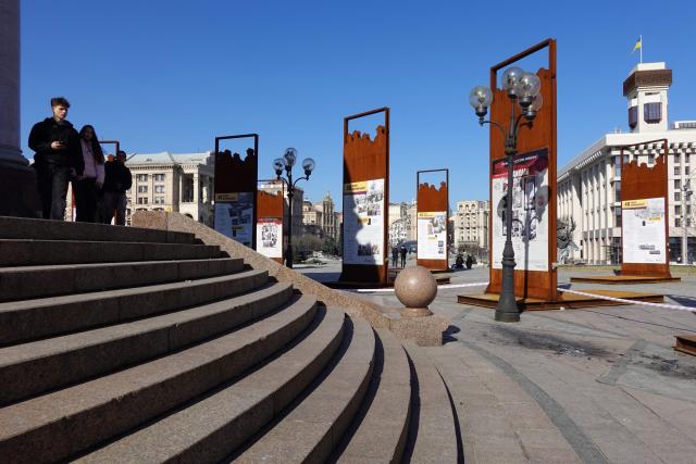 Pedestrians visit the crash site of drone fragments on Independence Square in Kyiv on March 16, 2026, amid the Russian invasion of Ukraine. Explosions rang out over the Ukrainian capital on March 16, 2026 and AFP journalists witnessed air defence batteries fending off a barrage of Russian projectiles during a rare daytime attack on Kyiv. (Photo by Maryke VERMAAK / AFP)
