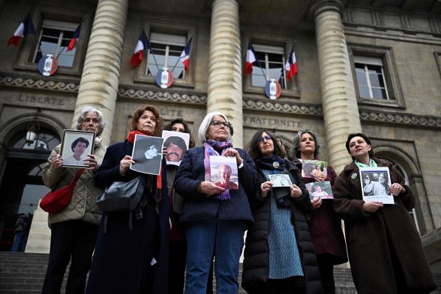 Relatives of the 170 victims of the 1989 bombing of the UTA DC-10 hold up portraits of the victims ahead of the opening of the appeal trial of former French President Nicolas Sarkozy, who is accused of soliciting Libyan funding for his 2007 election campaign, at the Paris Appeal Court in the Palais de Justice courthouse in Paris on March 16, 2026. The Paris Criminal Court Paris in September 2025 found Sarkozy guilty of criminal conspiracy and was handed a 5-year prison sentence over seeking to acquire funding from Muammar Gaddafi's Libya for the campaign that saw him elected. The right-wing politician -- who has denied any wrongdoing -- entered entered a Paris jail in October 2025, serving 20 days before he was released under judicial supervision. (Photo by JULIEN DE ROSA / AFP)