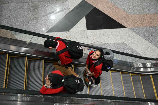 Members of Iran's women's football team use an escalator at the Kuala Lumpur International Airport in Sepang on March 16, 2026, after staying in a hotel in the Malaysian capital while awaiting the next leg of their journey home. Three more members of the Iranian women's football team have left their asylum in Australia and decided to return home, Canberra said on March 15. (Photo by MOHD RASFAN / AFP)