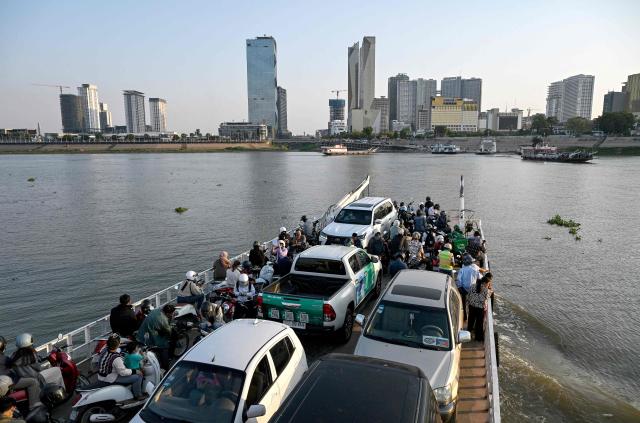 A ferry transports passengers and vehicles across the Mekong River in Phnom Penh on March 16, 2026. (Photo by TANG CHHIN Sothy / AFP)