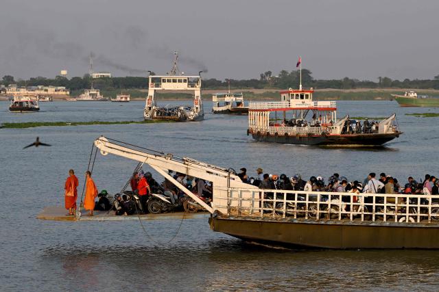 Ferries transport passengers and vehicles across the Mekong River in Phnom Penh on March 16, 2026. (Photo by TANG CHHIN Sothy / AFP)
