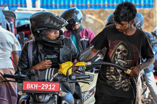 An employee fills petrol in a motorbike at a filling station in Wellawatte on the outskirts of Colombo on March 16, 2026. (Photo by Ishara S. KODIKARA / AFP)