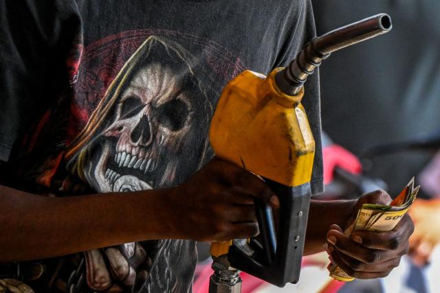 An employee collects cash after filling petrol in a motorbike at a filling station in Wellawatte on the outskirts of Colombo on March 16, 2026. (Photo by Ishara S. KODIKARA / AFP)