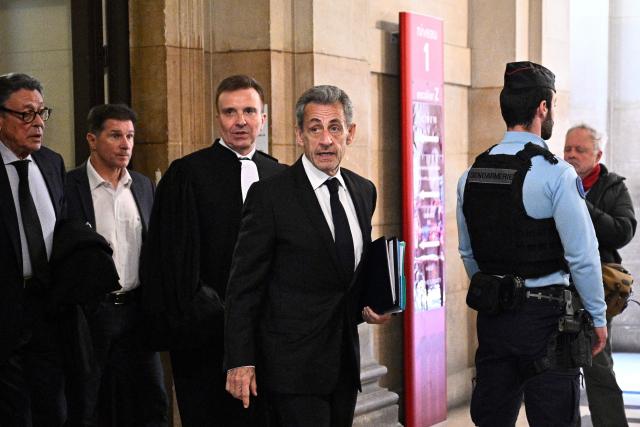 France's former president Nicolas Sarkozy (C) walks with his lawyer Jean-Michel Darrois (L) as he arrives for the opening of his appeal trial over charges he sought Libyan financing for his 2007 election, at the Paris Appeal Court in the Palais de Justice courthouse in Paris on March 16, 2026. The Paris Criminal Court in September 2025 convicted Sarkozy of criminal conspiracy and handed him a 5-year prison sentence over what it said was a scheme to acquire funding from Muammar Gaddafi's Libya for his 2007 presidential run that saw him elected. The right-wing politician -- who has denied any wrongdoing -- entered a Paris jail in October 2025, serving 20 days before he was released under judicial supervision. (Photo by JULIEN DE ROSA / AFP)
