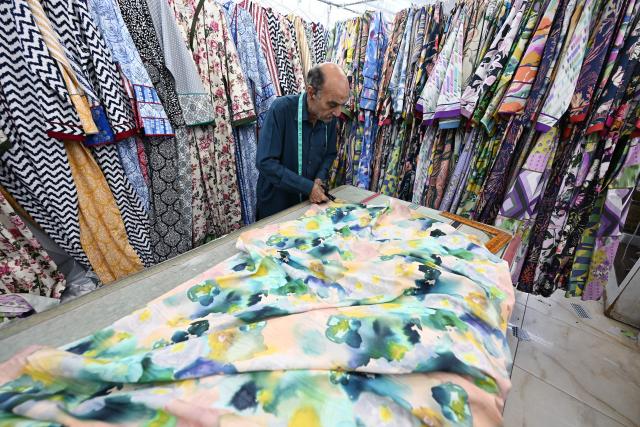 A tailor works at a custom clothing store in a traditional market in Kuwait City on March 16, 2026, ahead of Eid al-Fitr, the holiday marking the end of the Muslim holy fasting month of Ramadan. (Photo by YASSER AL-ZAYYAT / AFP)