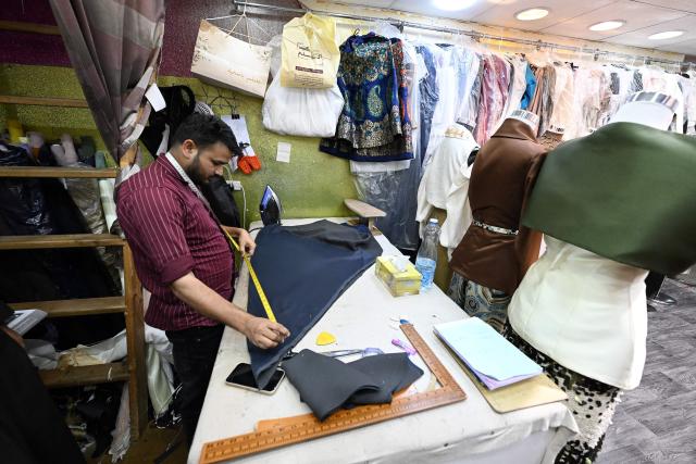 A tailor works at a custom clothing store in a traditional market in Kuwait City on March 16, 2026, ahead of Eid al-Fitr, the holiday marking the end of the Muslim holy fasting month of Ramadan. (Photo by YASSER AL-ZAYYAT / AFP)
