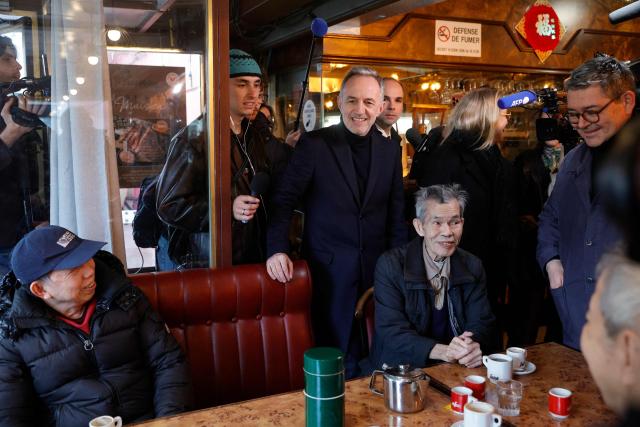 Socialist party (PS) mayoral candidate for Paris Emmanuel Gregoire (C) visits a cafe during a stroll through the Olympiades neighbourhood as part of his electoral campaign in Paris on March 16, 2026, a day after the first round of municipal elections in France. In Paris, Socialist candidate Emmanuel Gregoire is in the lead ahead of former culture minister Rachida Dati. Gregoire has promised to carry on the legacy of outgoing Socialist mayor Anne Hidalgo, including increasing the number of bike lanes and green spaces and improving public housing in the densely populated city of two million people. (Photo by GEOFFROY VAN DER HASSELT / AFP)
