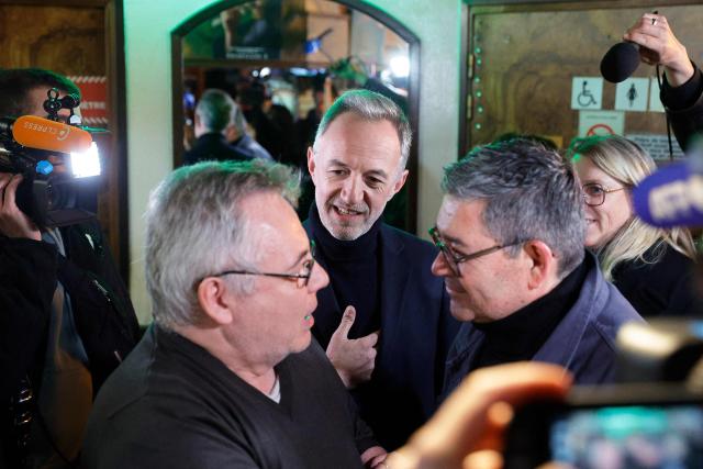 Socialist party (PS) mayoral candidate for Paris Emmanuel Gregoire (C) and reelected PS Mayor of Paris' 13th arrondissement Jerome Coumet (R)  speak with a local business owner as they visit a cafe during a stroll through the Olympiades neighbourhood as part of his electoral campaign in Paris on March 16, 2026, a day after the first round of municipal elections in France. In Paris, Socialist candidate Emmanuel Gregoire is in the lead ahead of former culture minister Rachida Dati. Gregoire has promised to carry on the legacy of outgoing Socialist mayor Anne Hidalgo, including increasing the number of bike lanes and green spaces and improving public housing in the densely populated city of two million people. (Photo by GEOFFROY VAN DER HASSELT / AFP)