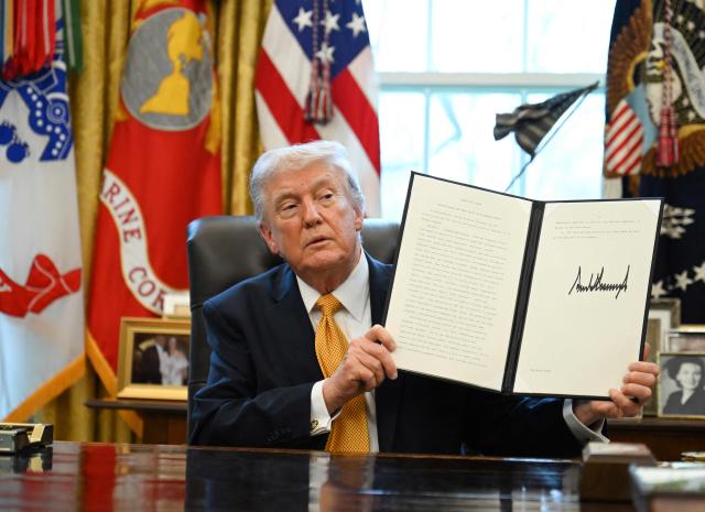 US President Donald Trump displays an executive order on fraud he signed in the Oval Office at the White House in Washington, DC, on March 16, 2026. (Photo by ANNABELLE GORDON / AFP)