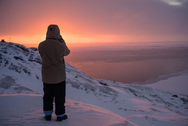 A boy takes a photo of the sunset in Ilulissat, Greenland, on March 16, 2026. (Photo by Florent VERGNES / AFP)