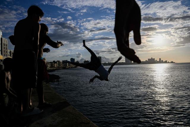 TOPSHOT - A young man jumps into the sea at sunset on the Malecon during a blackout in Havana on March 16, 2026. Cuba suffered a widespread power cut on March 16, 2026, according to the national electricity company, against the backdrop of a severe crisis on the island caused by the US energy blockade. (Photo by Yamil LAGE / AFP)