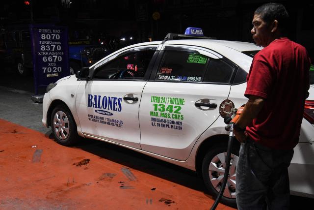 A taxi driver fills up his vehicle with gasoline prior to a fuel price increase at a petrol station in Manila on March 17, 2026. Oil climbed again in Asia on March 17 after prices retreated a day earlier, with investors remaining focused on the Strait of Hormuz. (Photo by Ted ALJIBE / AFP)