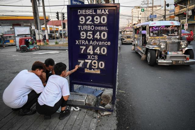 Workers change the price label of fuel at a petrol station in Manila on March 17, 2026. Oil climbed again in Asia on March 17 after prices retreated a day earlier, with investors remaining focused on the Strait of Hormuz. (Photo by Ted ALJIBE / AFP)