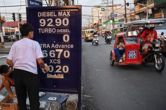 Workers change the price label of fuel at a petrol station in Manila on March 17, 2026. Oil climbed again in Asia on March 17 after prices retreated a day earlier, with investors remaining focused on the Strait of Hormuz. (Photo by Ted ALJIBE / AFP)
