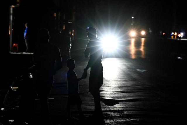 People stand on a street during a blackout in Havana on March 16, 2026. Cuba suffered a widespread power cut on March 16, 2026, according to the national electricity company, against the backdrop of a severe crisis on the island caused by the US energy blockade. (Photo by Yamil LAGE / AFP)