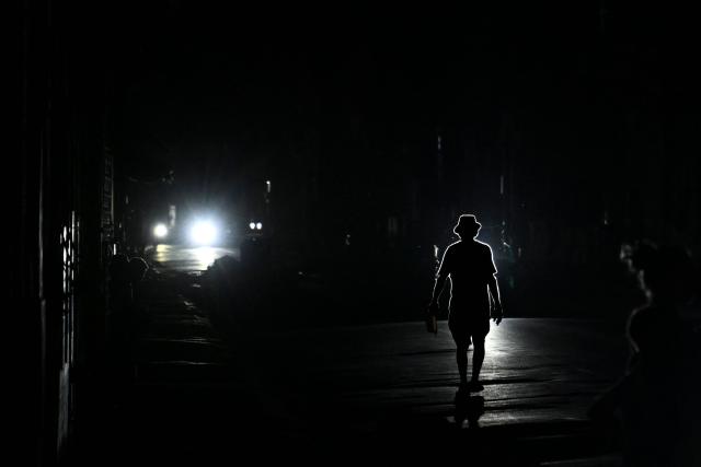 A man walks on a street during a blackout in Havana on March 16, 2026. Cuba suffered a widespread power cut on March 16, 2026, according to the national electricity company, against the backdrop of a severe crisis on the island caused by the US energy blockade. (Photo by Yamil LAGE / AFP)