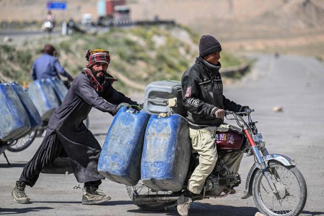This photograph taken on March 14, 2026 shows vendors transporting jerrycans filled with smuggled Iranian petrol on their motorcycles, on the outskirts of Quetta in Balochistan province. (Photo by Banaras KHAN / AFP)