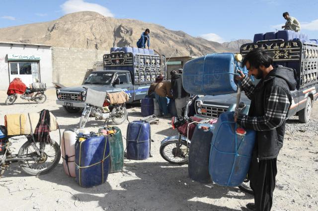 This photograph taken on March 14, 2026 shows vendors preparing to fill their jerrycans with smuggled Iranian petrol, on the outskirts of Quetta in Balochistan province. (Photo by Banaras KHAN / AFP)