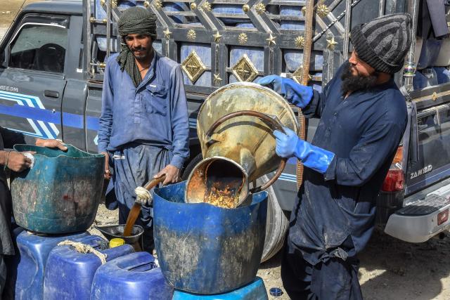 This photograph taken on March 14, 2026 shows vendors filling their jerrycans with smuggled Iranian petrol, on the outskirts of Quetta in Balochistan province. (Photo by Banaras KHAN / AFP)