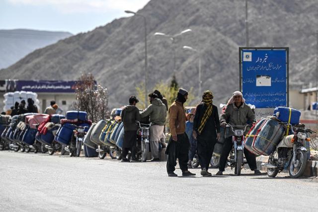 This photograph taken on March 14, 2026 shows vendors preparing to transport jerrycans  filled with smuggled Iranian petrol on their motorcycles, on the outskirts of Quetta in Balochistan province. (Photo by Banaras KHAN / AFP)