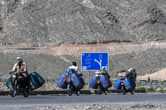 This photograph taken on March 14, 2026 shows vendors transporting jerrycans filled with smuggled Iranian petrol on their motorcycles, on the outskirts of Quetta in Balochistan province. (Photo by Banaras KHAN / AFP)