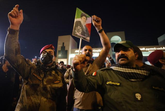 A photo of slain Iranian supreme leader Ayatollah Ali Khamenei is held as mourners attend a funeral for members of Iraq's Hashed al-Shaabi, who were killed in an attack in al-Qaim province near the Syria border the previous evening, in Baghdad on March 17, 2026. (Photo by AHMAD AL-RUBAYE / AFP) / 