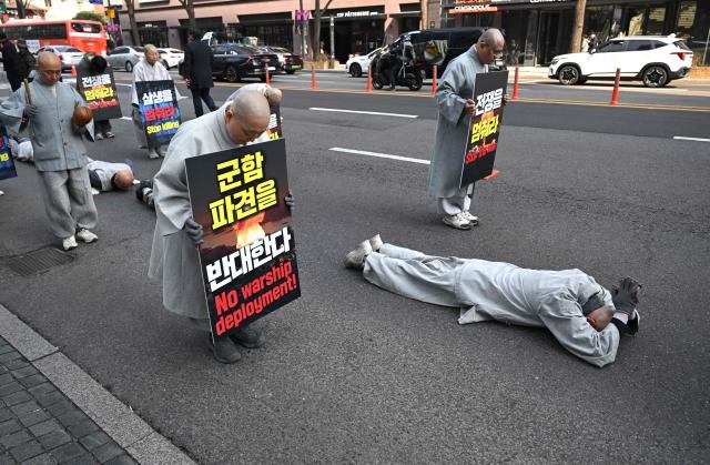South Korean Buddhist monks perform full bows as they march towards the US embassy during a protest against the war on Iran in Seoul on March 17, 2026. (Photo by Jung Yeon-je / AFP)